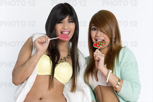 Two young Asian women posing with lollipops