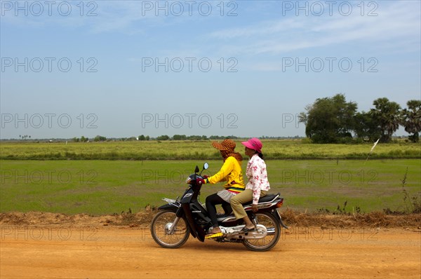 Two women riding on a motorcycle on a country road