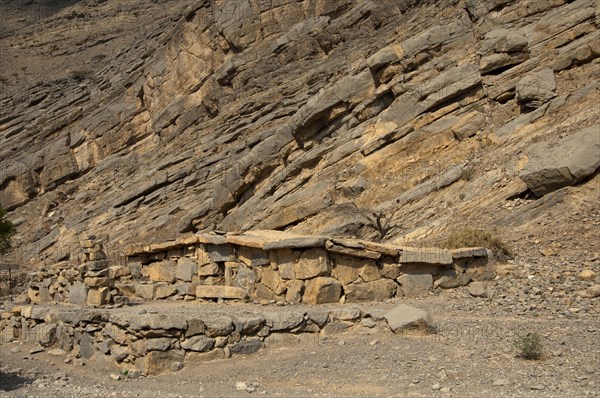 Bedouin stone house matching in colour and texture to the foot of a cliff in the mountains of Musandam