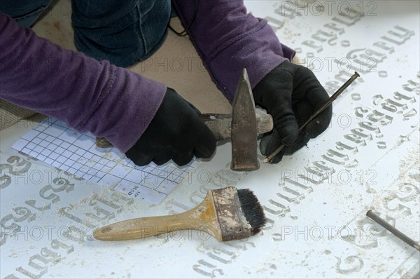 Stonemason chiselling Khmer characters into a gravestone in a stone cutting factory