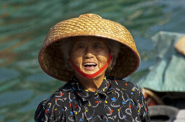 Laughing old Chinese fishmonger with straw hat