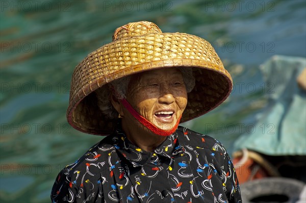 Laughing old Chinese fishmonger with straw hat