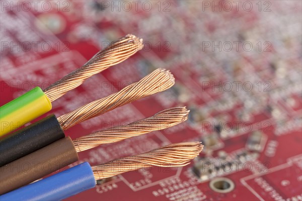 Copper wires in front of a red circuit board