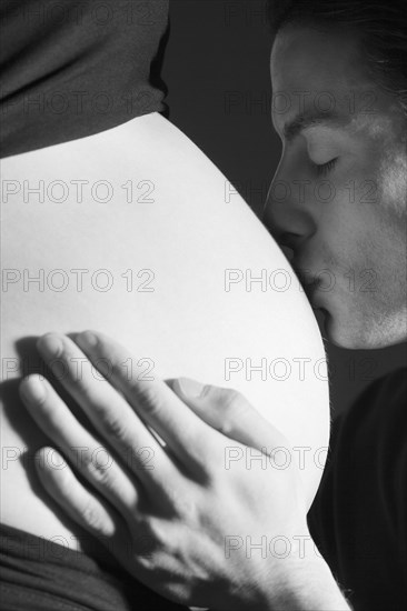 Expectant father is kissing the belly of his pregnant partner