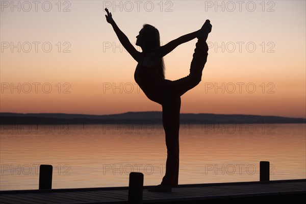 Silhouette of a woman practicing yoga against the light of the evening sun