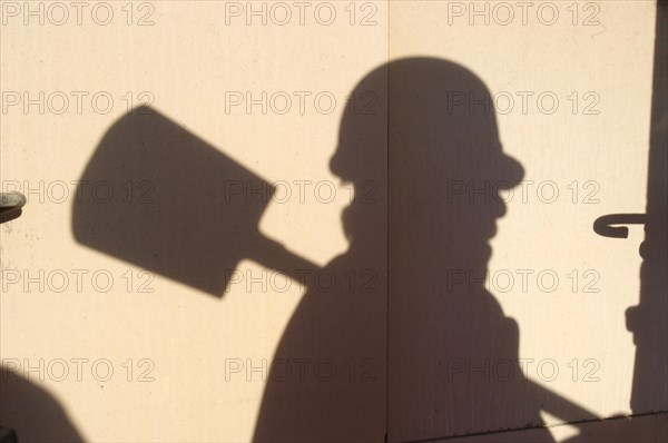 Shadow of a worker with hard hat and spade