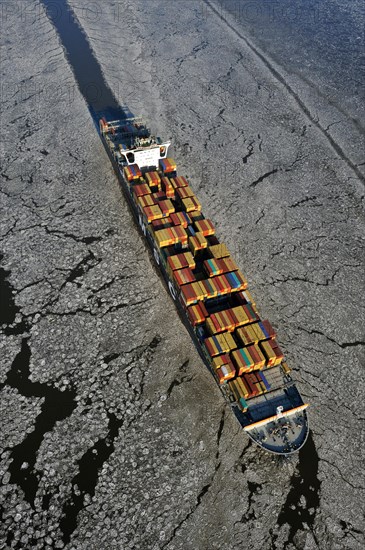 Container ship on the Elbe River with ice flow