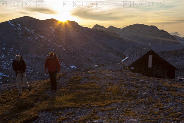 Two hikers at Edelweisserhuette refuge at sunset