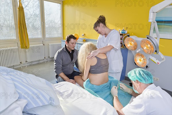 Pregnant women during delivery in the delivery room with an anesthesiologist applying a PDA or epidural