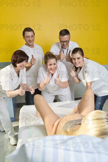 Several doctors and midwives encouraging a woman during childbirth with their thumbs up