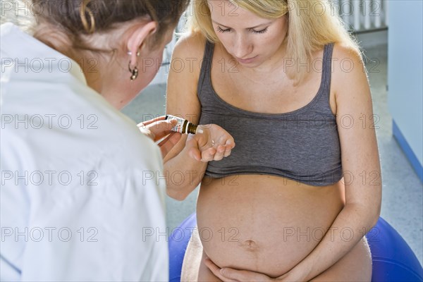 Pregnant woman recieving homeopathic medicine from her midwife during delivery