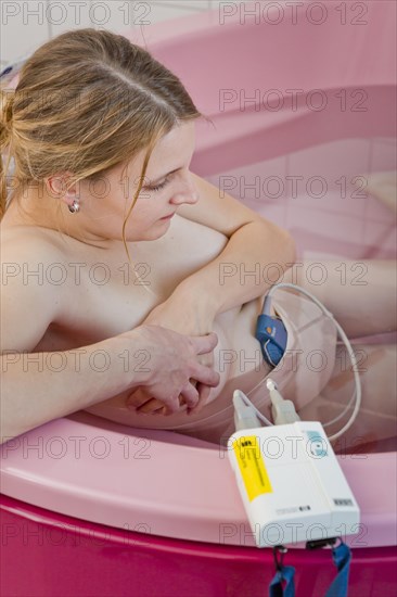 Woman during childbirth with a cardiotocography or CTG in a birthing bath in the maternity delivery room