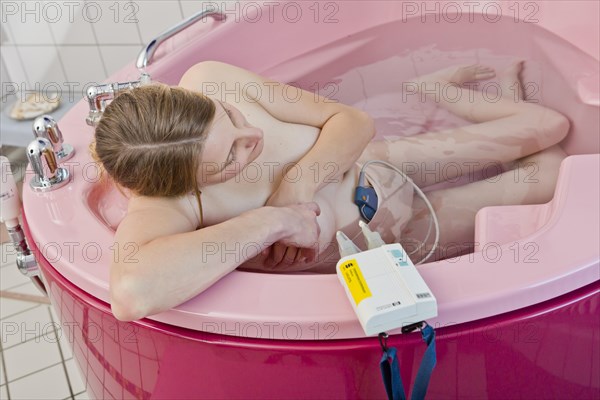 Woman during childbirth with a cardiotocography or CTG in a birthing bath in the maternity delivery room