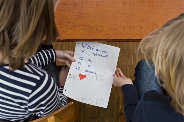 School children secretly passing notes under the school desk