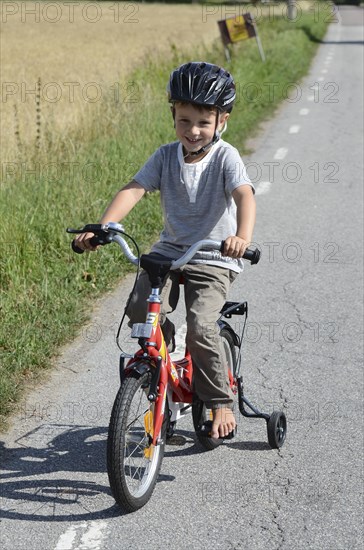 Boy riding a bicycle with training wheels