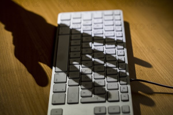 Shadow of a hand on a computer keyboard