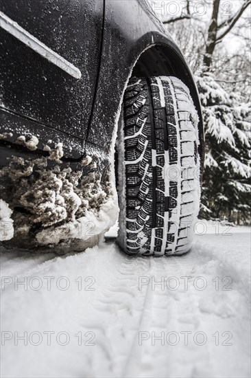 Car with winter tyres parked on a road covered with snow