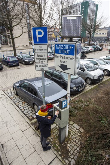 Woman purchasing a parking ticket from a solar powered parking ticket vending machine