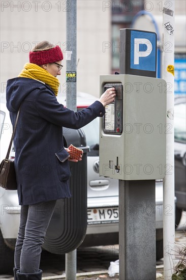 Woman purchasing a parking ticket from a parking ticket vending machine