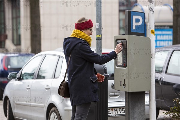 Woman purchasing a parking ticket from a parking ticket vending machine