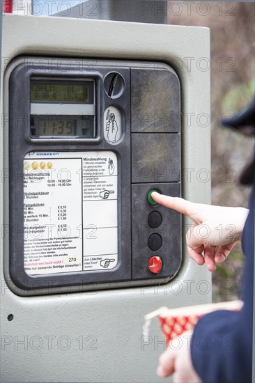 Woman purchasing a parking ticket from a parking ticket vending machine