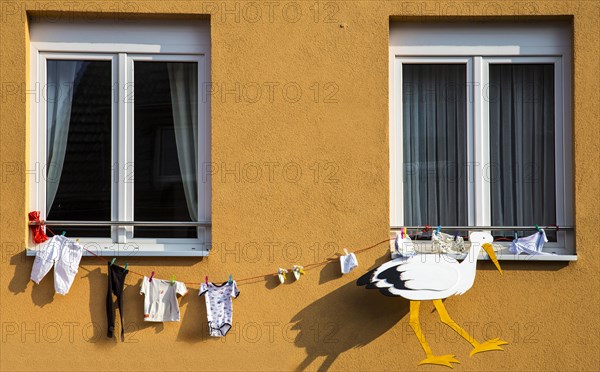 Stork figure and baby clothing attached to a house