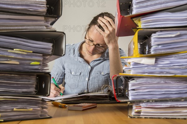 Woman working at a desk between stacks of files