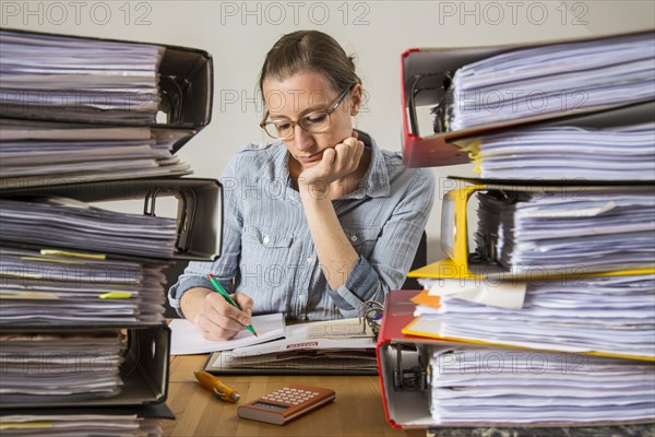 Woman working at a desk between stacks of files