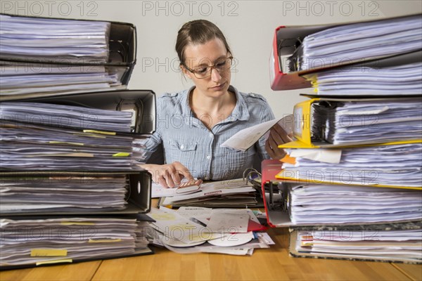 Woman working at a desk between stacks of files