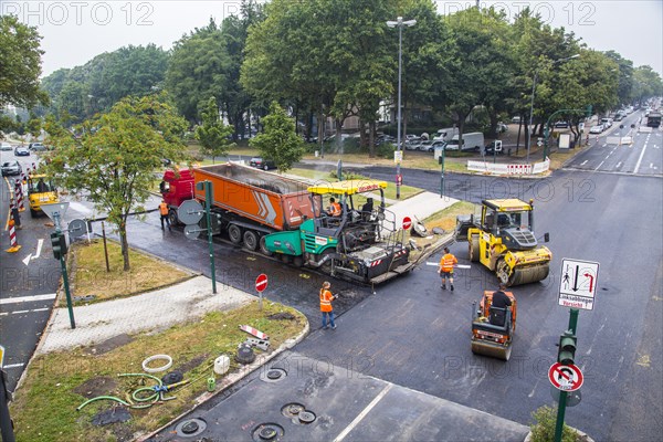 Rolling machines and an asphalt spreader during asphalt work on a large urban road construction site