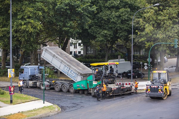 Rolling machine and an asphalt spreader during asphalt work on a large urban road construction site