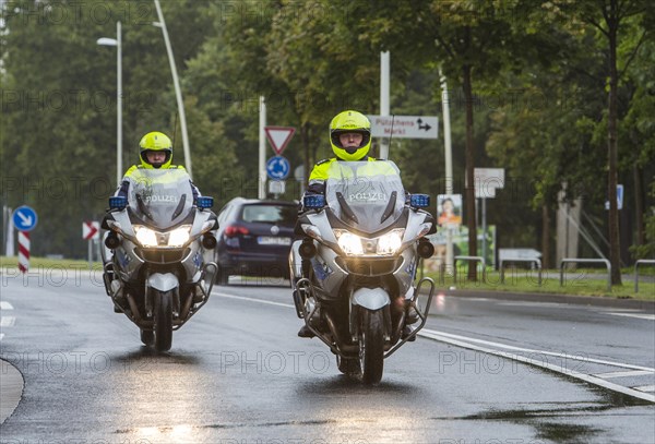 Policemen wearing yellow helmets on motorcycles