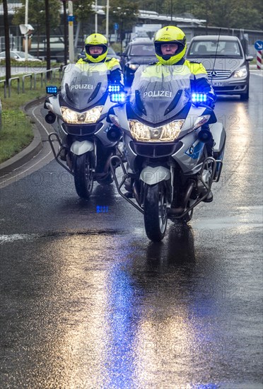 Policemen wearing yellow helmets on motorcycles