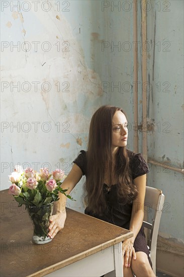 Young woman sitting at a table with flowers in a vase