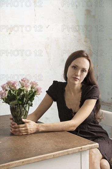Young woman sitting at a table with flowers in a vase