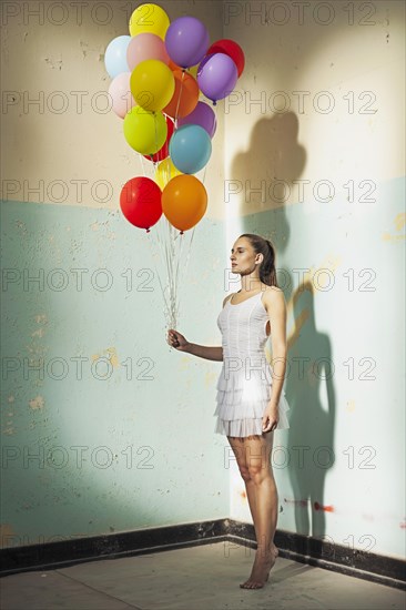 Young woman holding balloons in a empty room