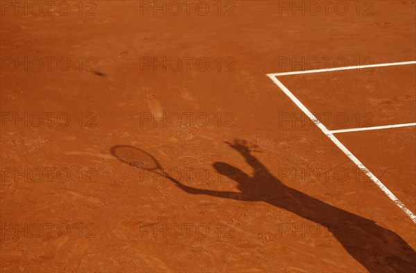 Shadow of a tennis player serving the ball