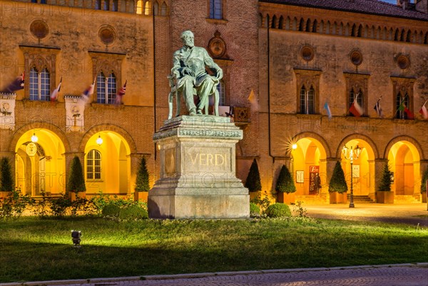 Illuminated Verdi monument in front of Rocca Pallavicino with Opera House Teatro Guiseppe Verdi