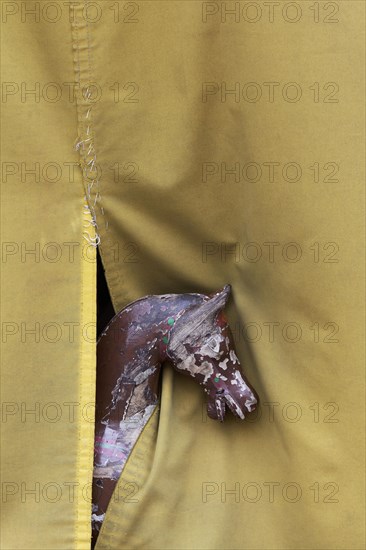 Old carousel horse looking out underneath a tarpaulin