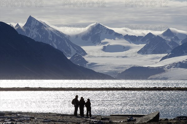 Silhouettes of expedition participants in front of the mountain and glacier scenery of Smeerenburgbreen