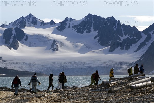 Expedition participants hiking near Smeerenburg in front of the mountain and glacier scenery of Vasahalvoya