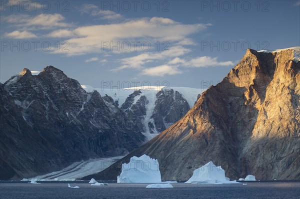 Icebergs in front of the mountain and glacier scenery in Vest Frederiksdal in the morning light