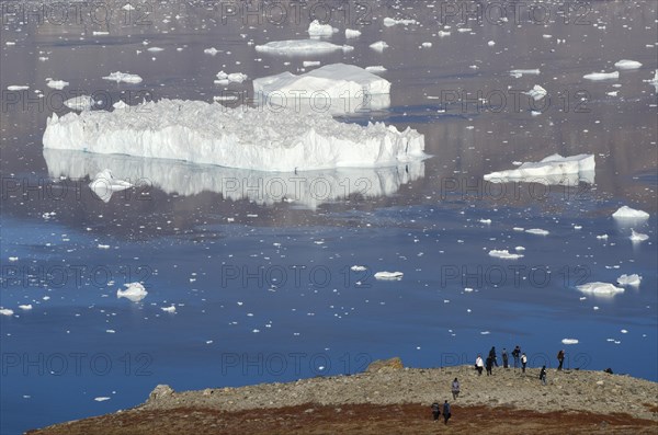 Hikers observing a very large iceberg
