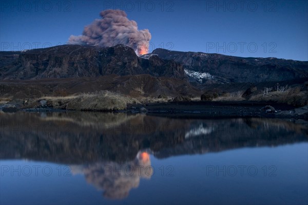 Eruption of Eyjafjallajoekull volcano with its reflection