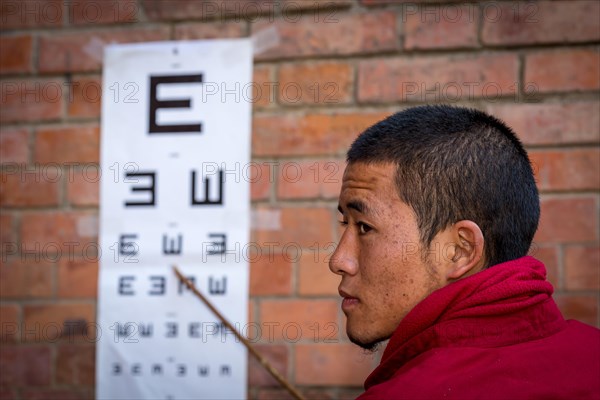 A monk from Amitabha Monastery carrying out a vision test for poor villagers