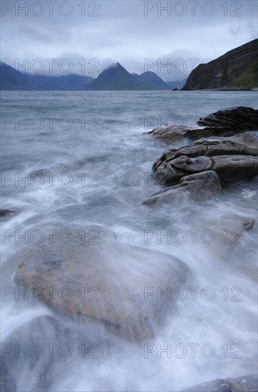 Mountains shrouded with clouds on a rocky seashore