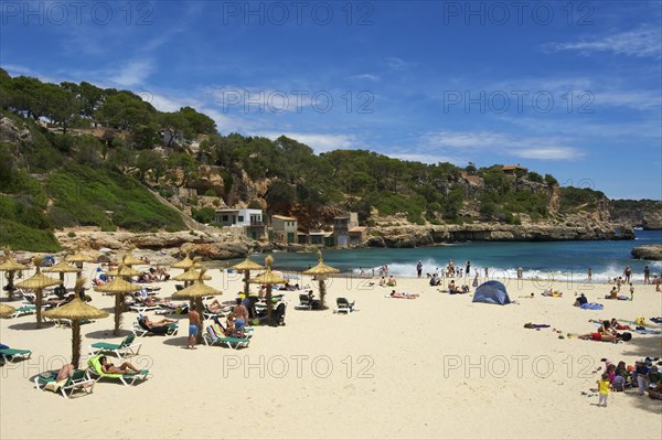 Tourists on the beach in the bay at Cala Llombards