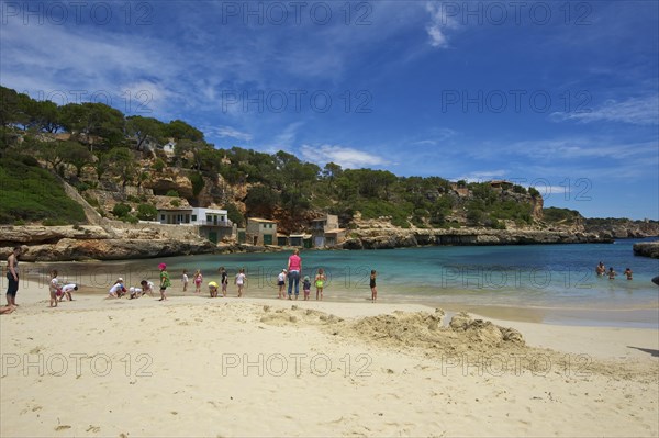 Tourists on the beach in the bay at Cala Llombards