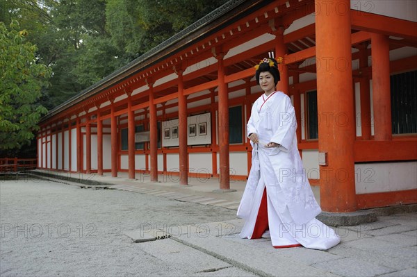 Bride in a traditional kimono with brocade holding a fan