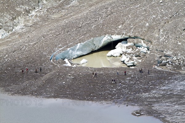 Hikers at the hole of collapsed ice in Pasterze Glacier